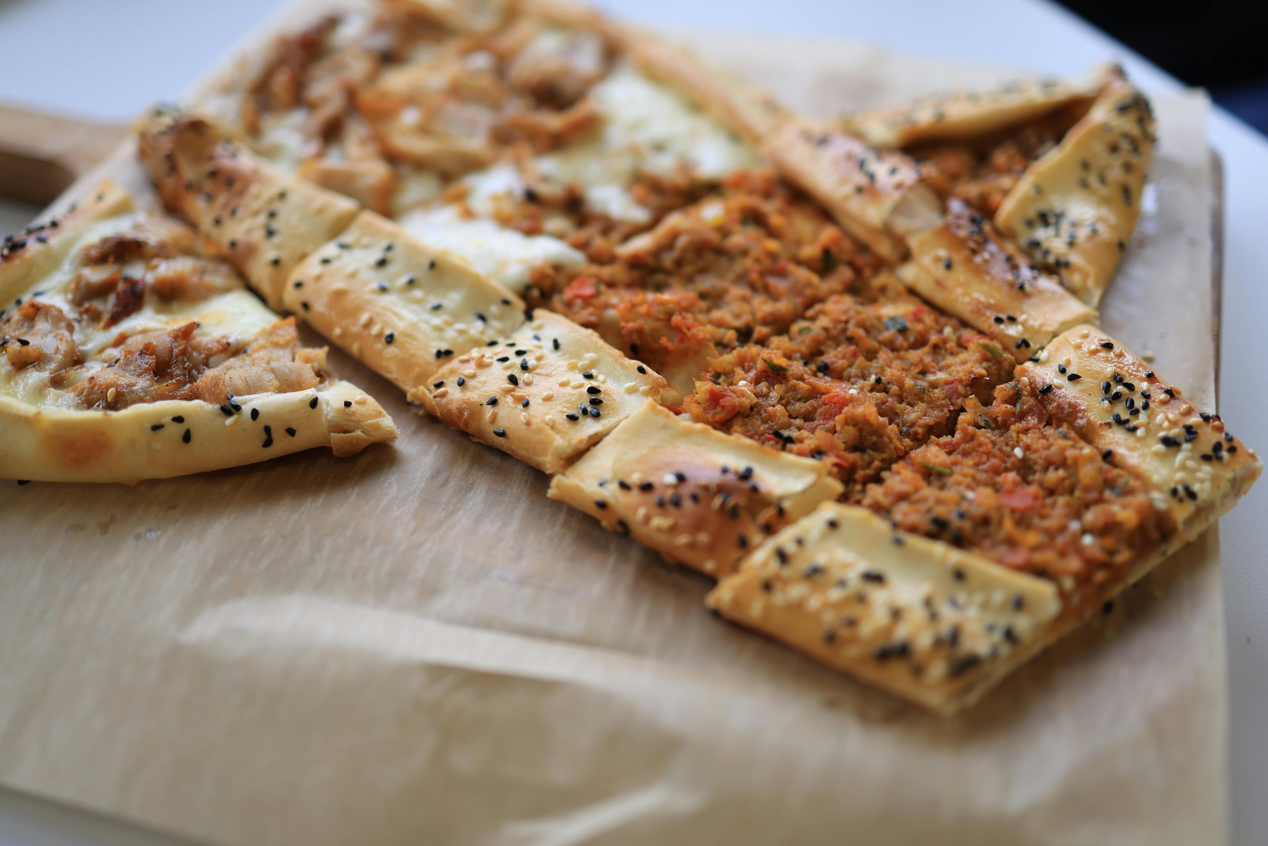 Delicious homemade Turkish pide topped with minced meat on a wooden board.